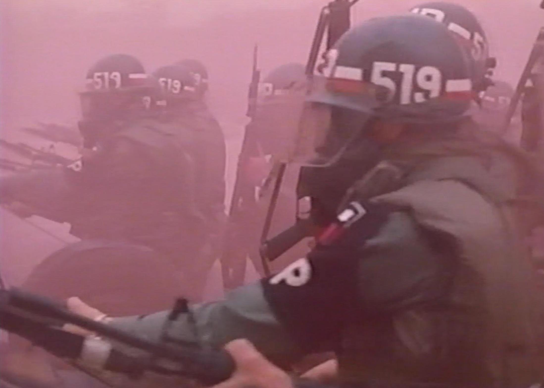 Military troops in helmets and gas masks walking with guns in a fog.