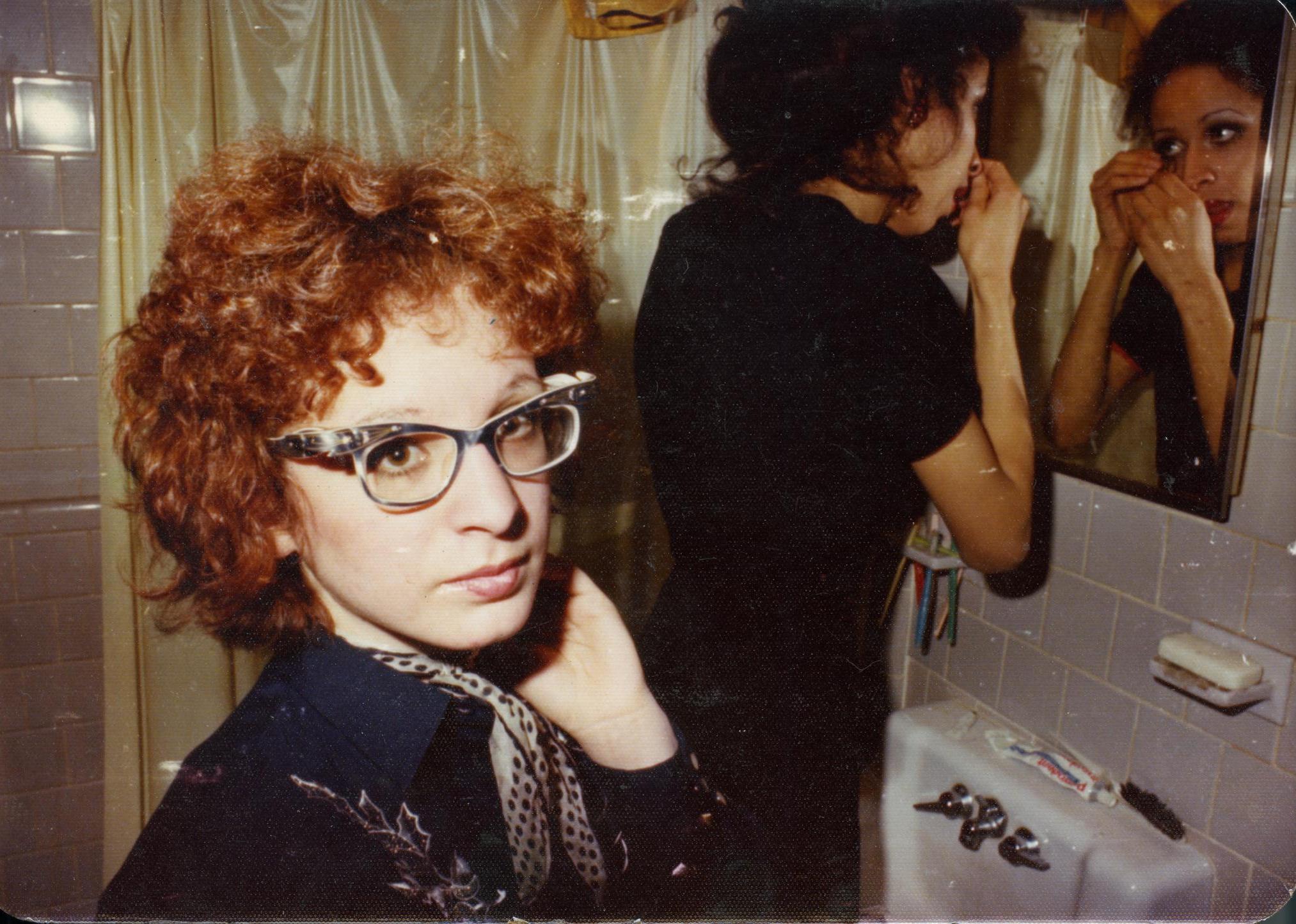 Two women in front of a bathroom mirror.
