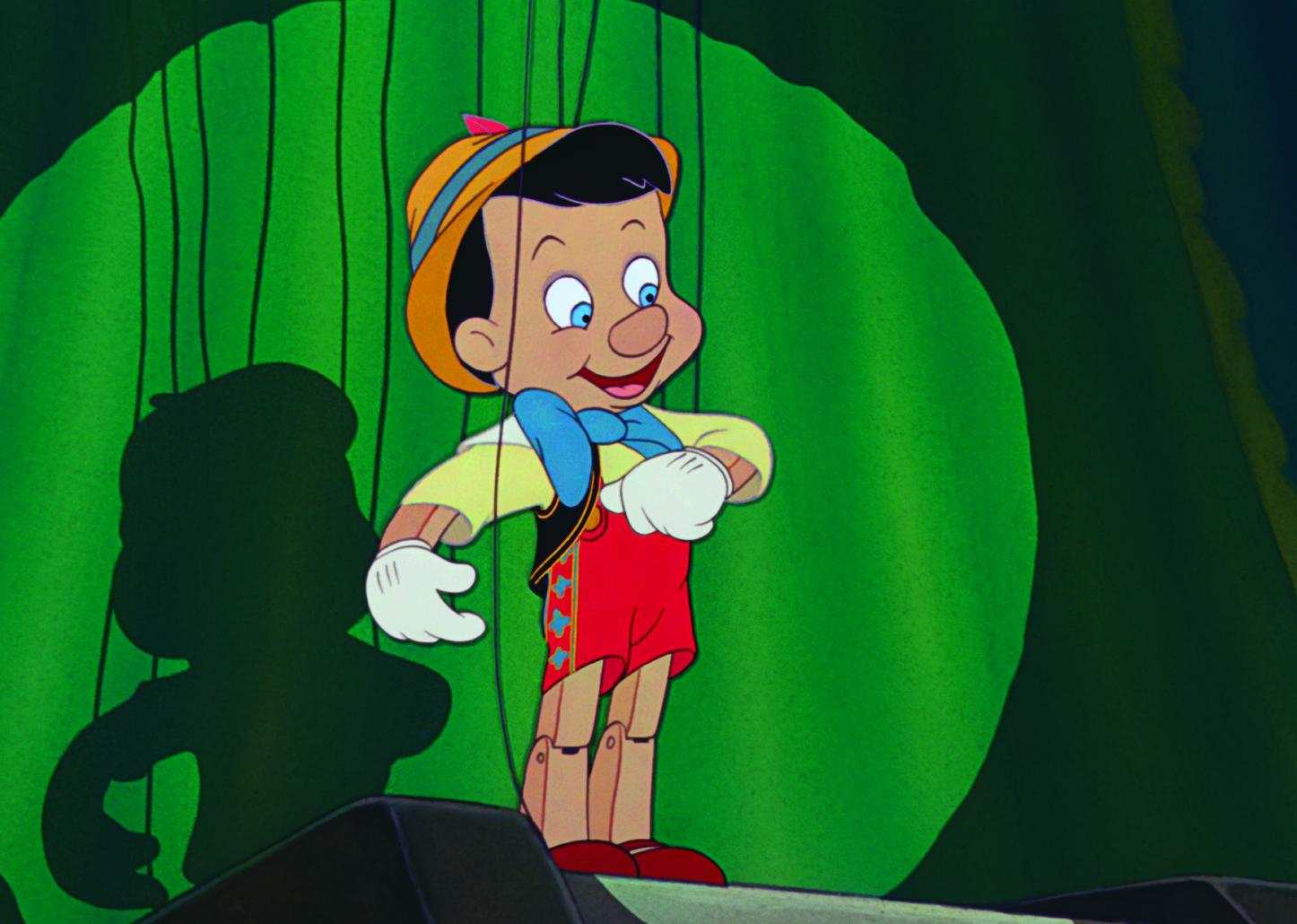 A cartoon of a Pinocchio, a puppet who is a little boy, onstage in front of a green curtain.