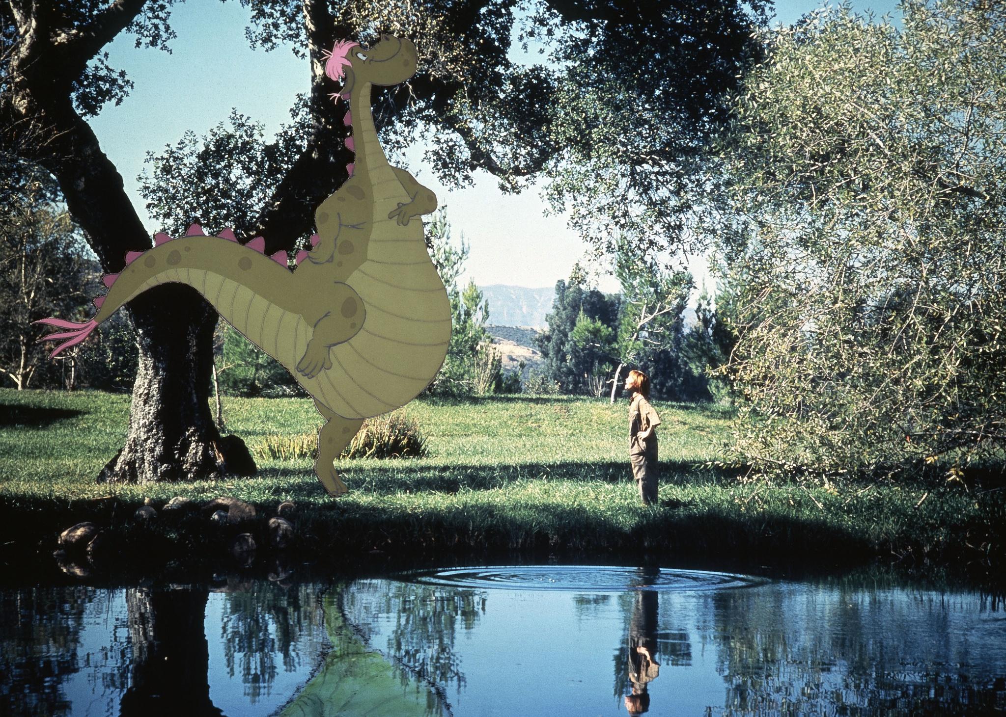 A boy in front of a pond next to a cartoon dragon.