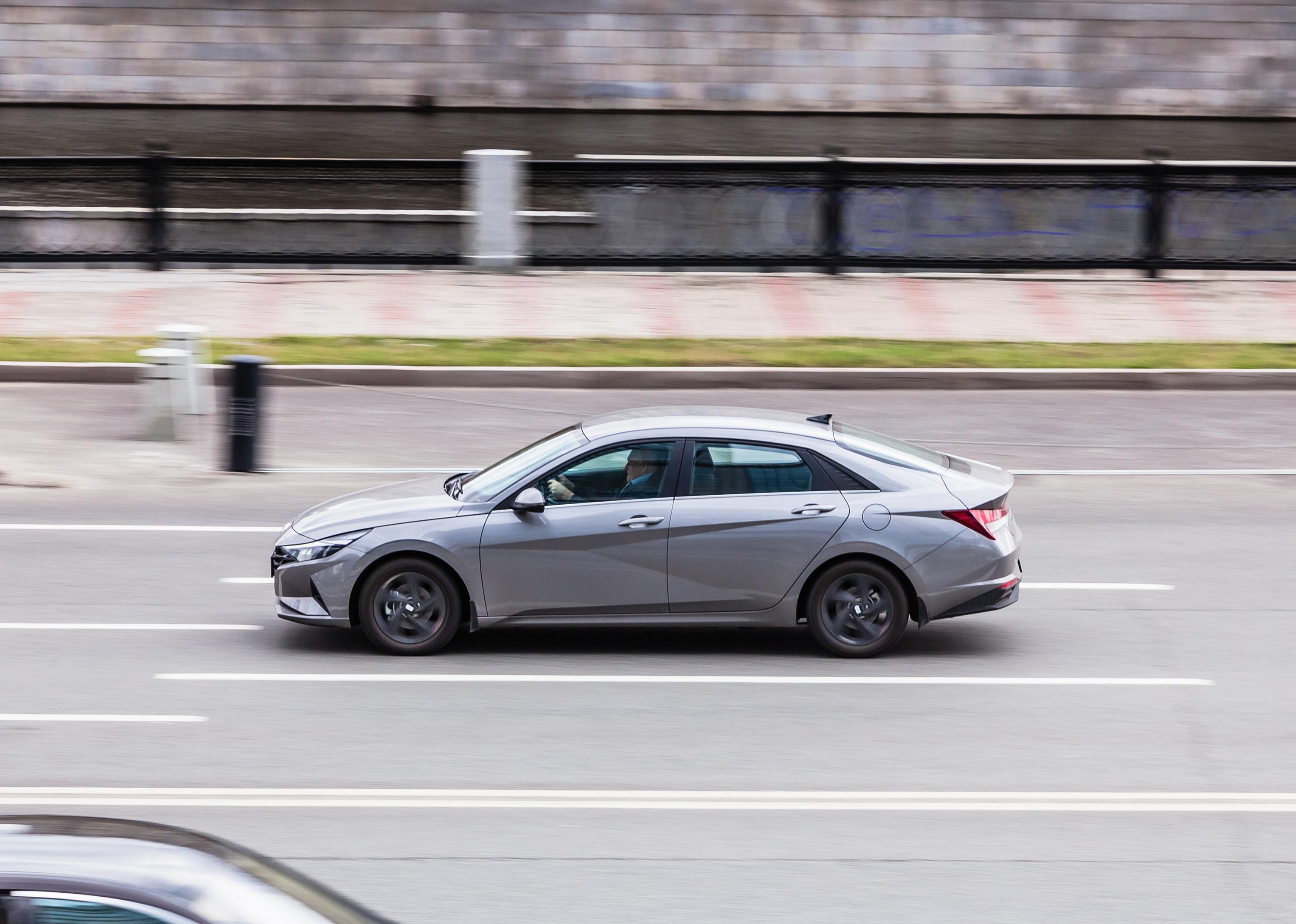 A silver Hyundai Elantra speeding down a road.