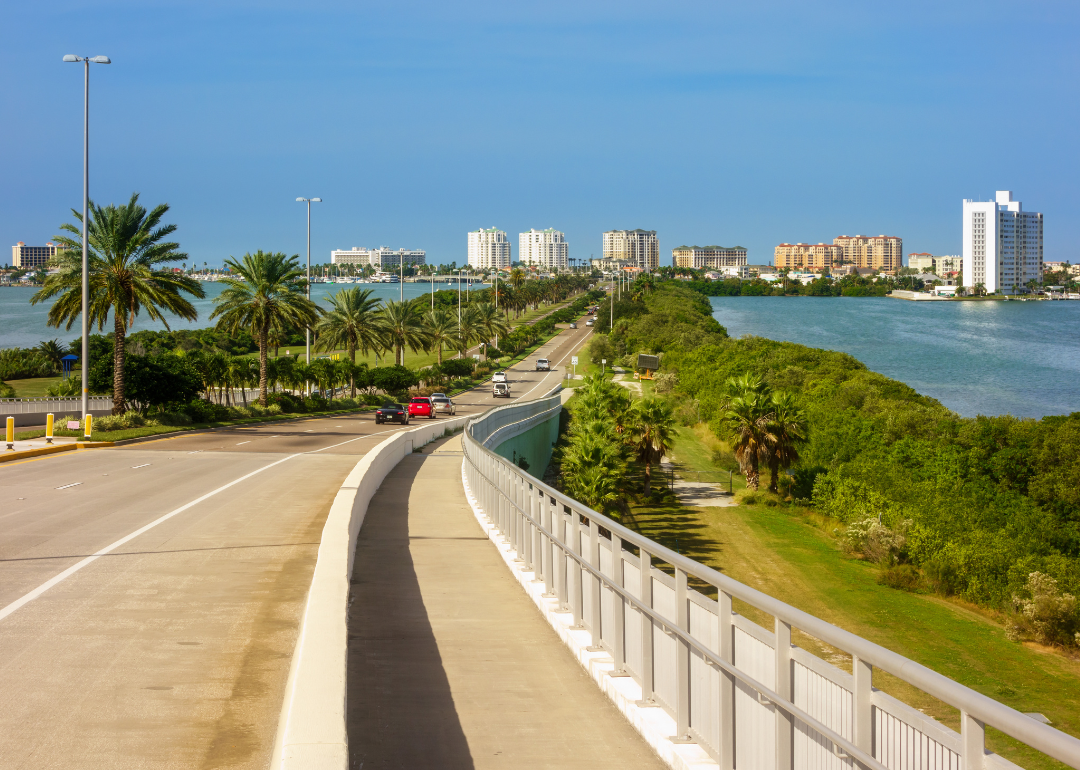 A highway lined with palm trees and water on both sides.