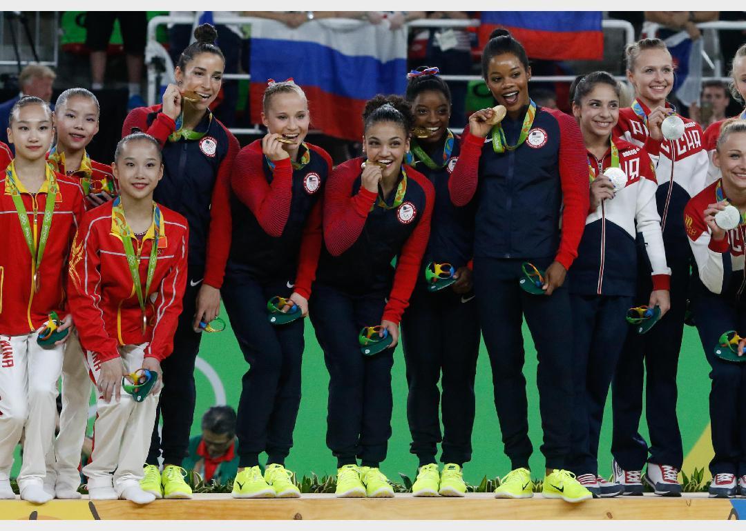 A group of young gymnasts from three different countries holding Olympic medals.