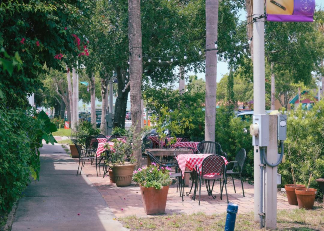 A small outdoor patio along the sidewalk with red and white checkered bistro tables.