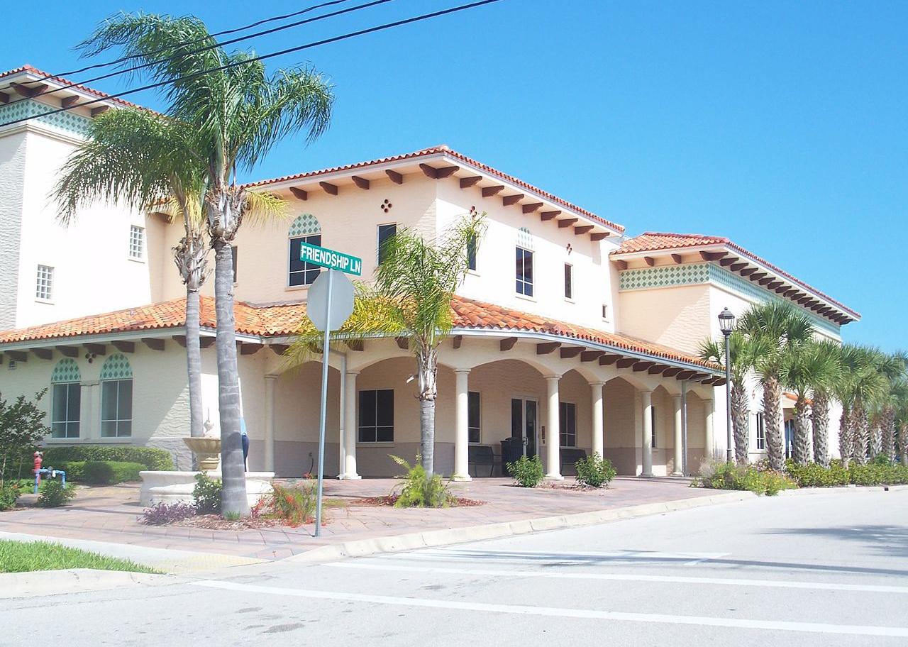 A pink stucco city hall with palm trees.