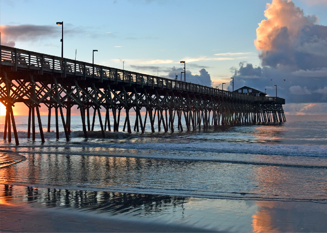 A long, tall pier going into the water from the beach.