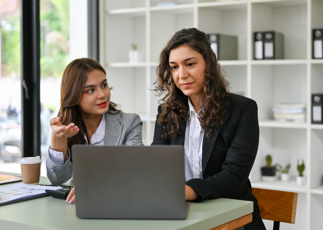 Two professional women discussing something over a laptop.