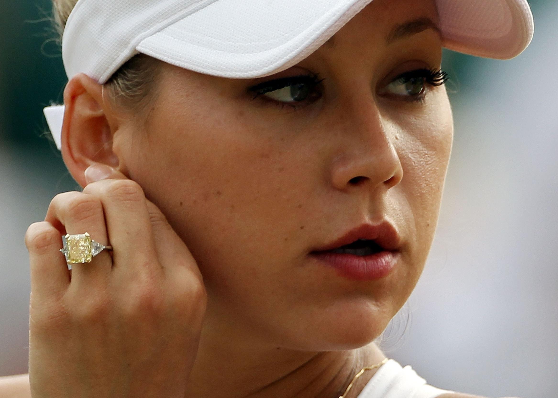 Anna Kournikova, in all white tennis gear, shows off her yellow engagement ring.