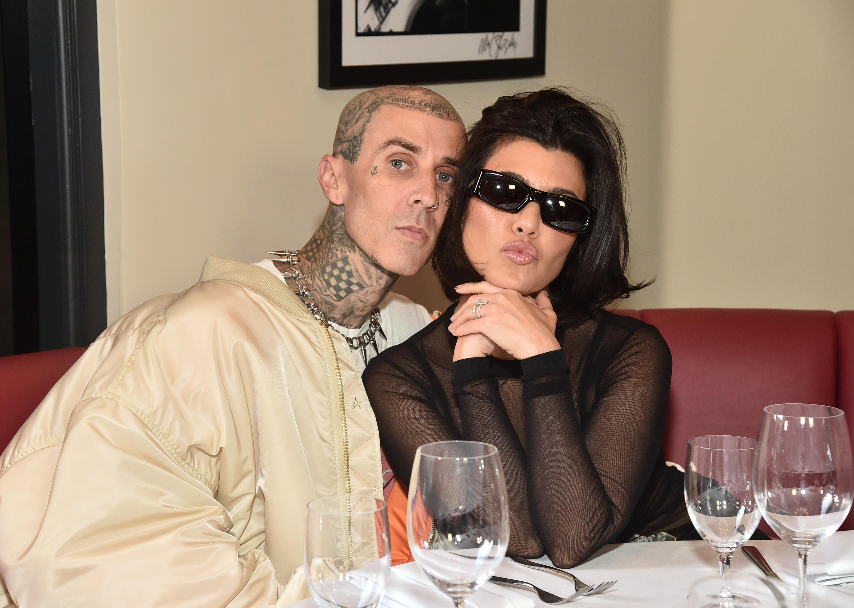 Kourtney Kardashian and Travis Barker sitting at a restaurant together.