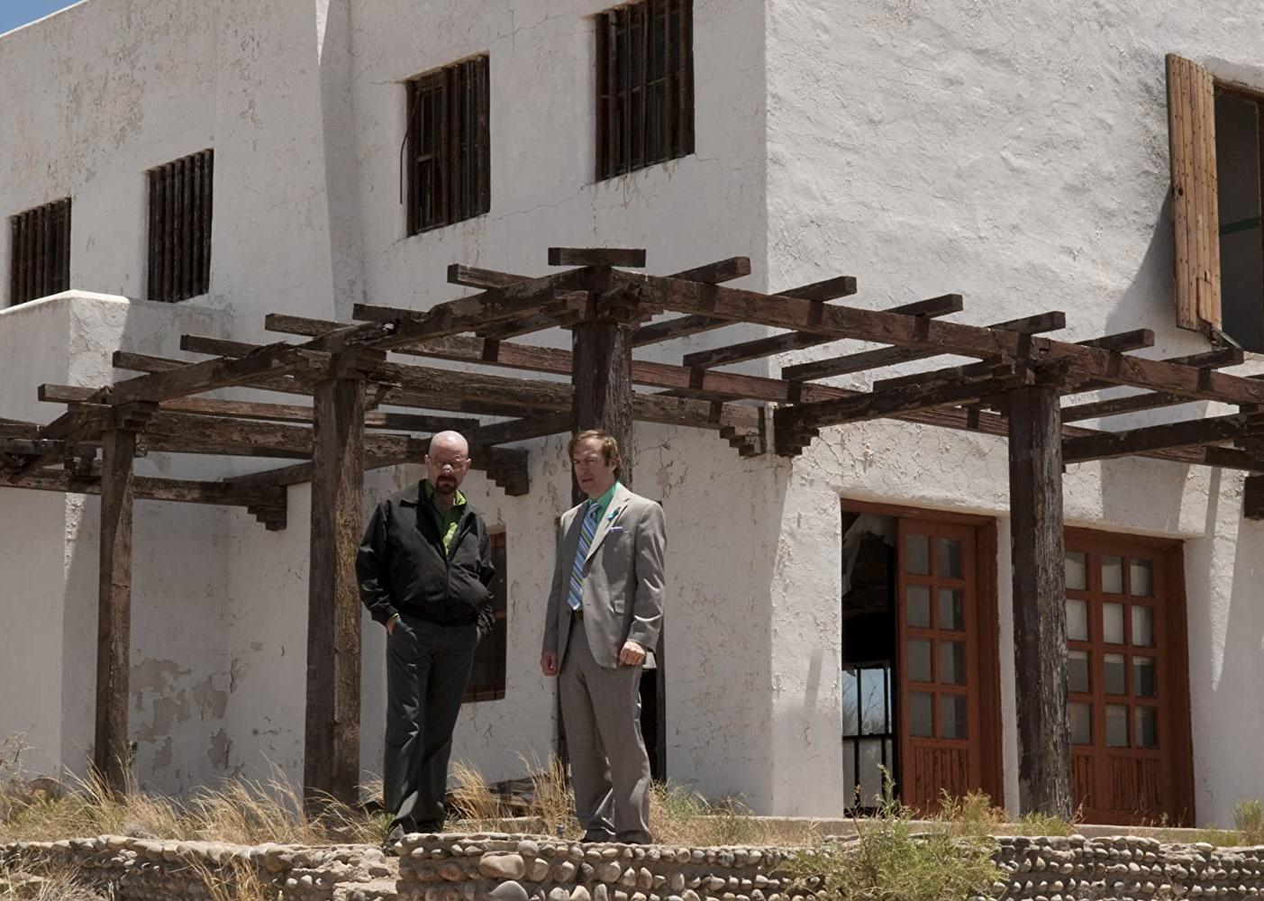 Bryan Cranston and Bob Odenkirk standing in front of a stucco building.