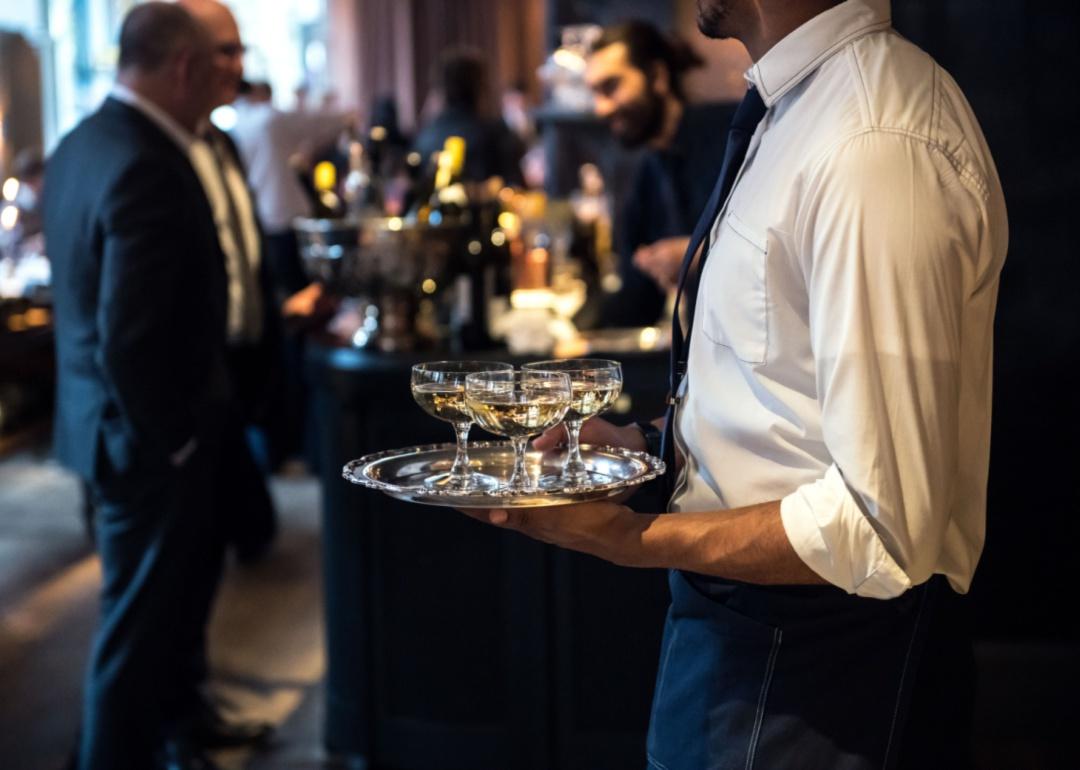 Waitstaff carrying trays of drinks.