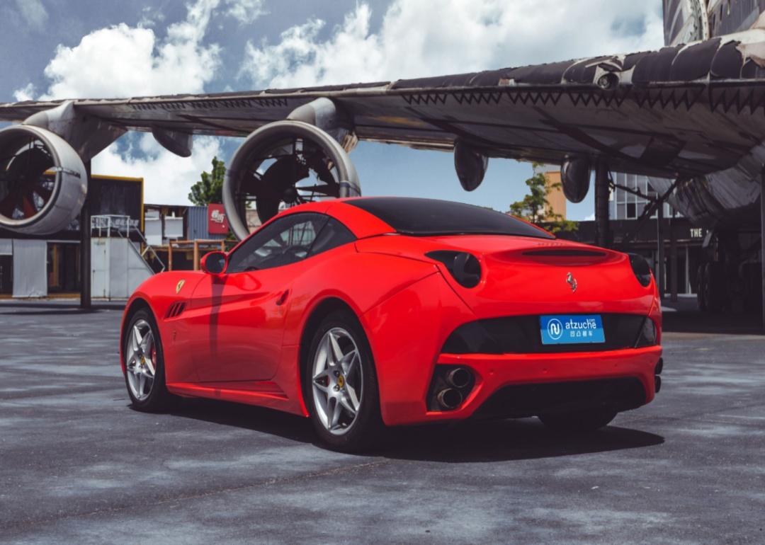 A red Ferrari California in front of an airplane.