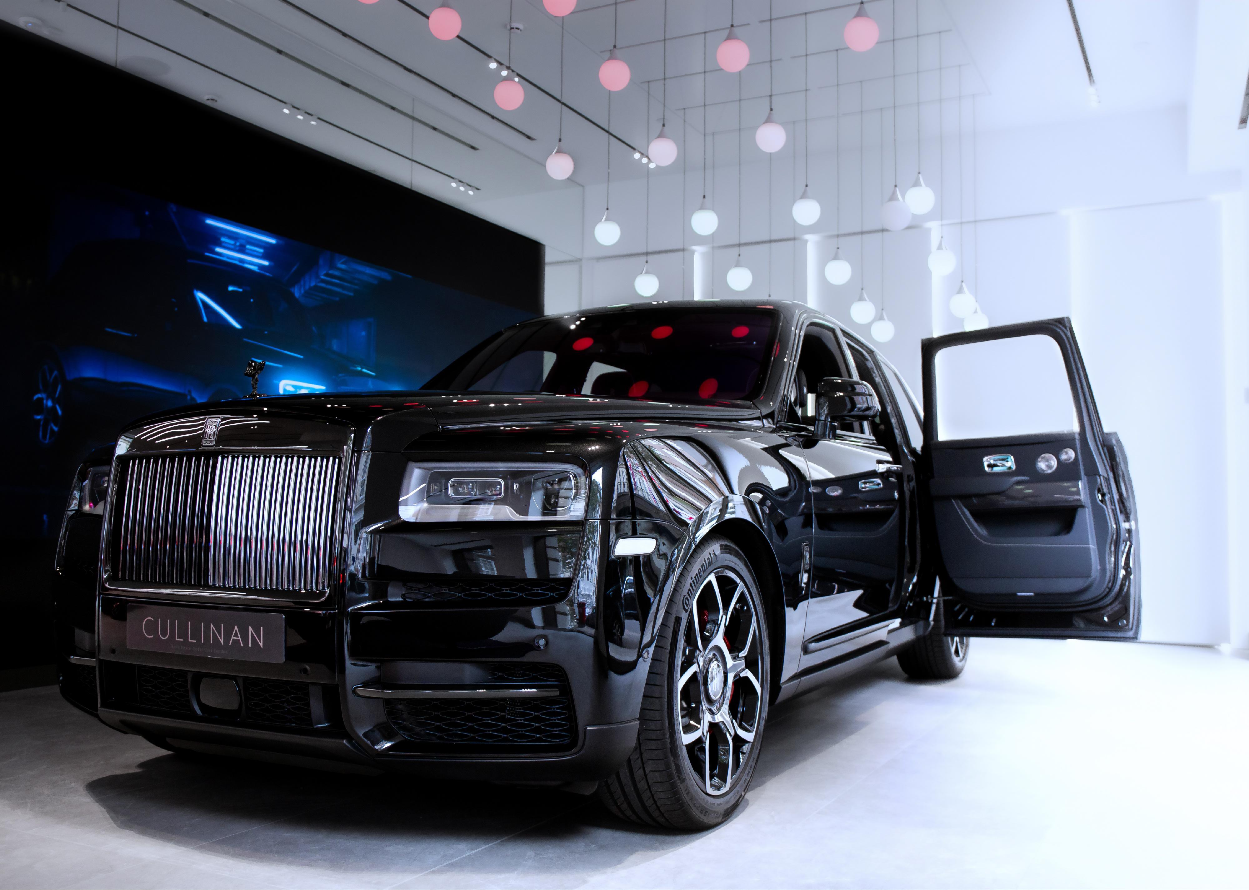 A black Rolls Royce Cullinan on a showroom floor.