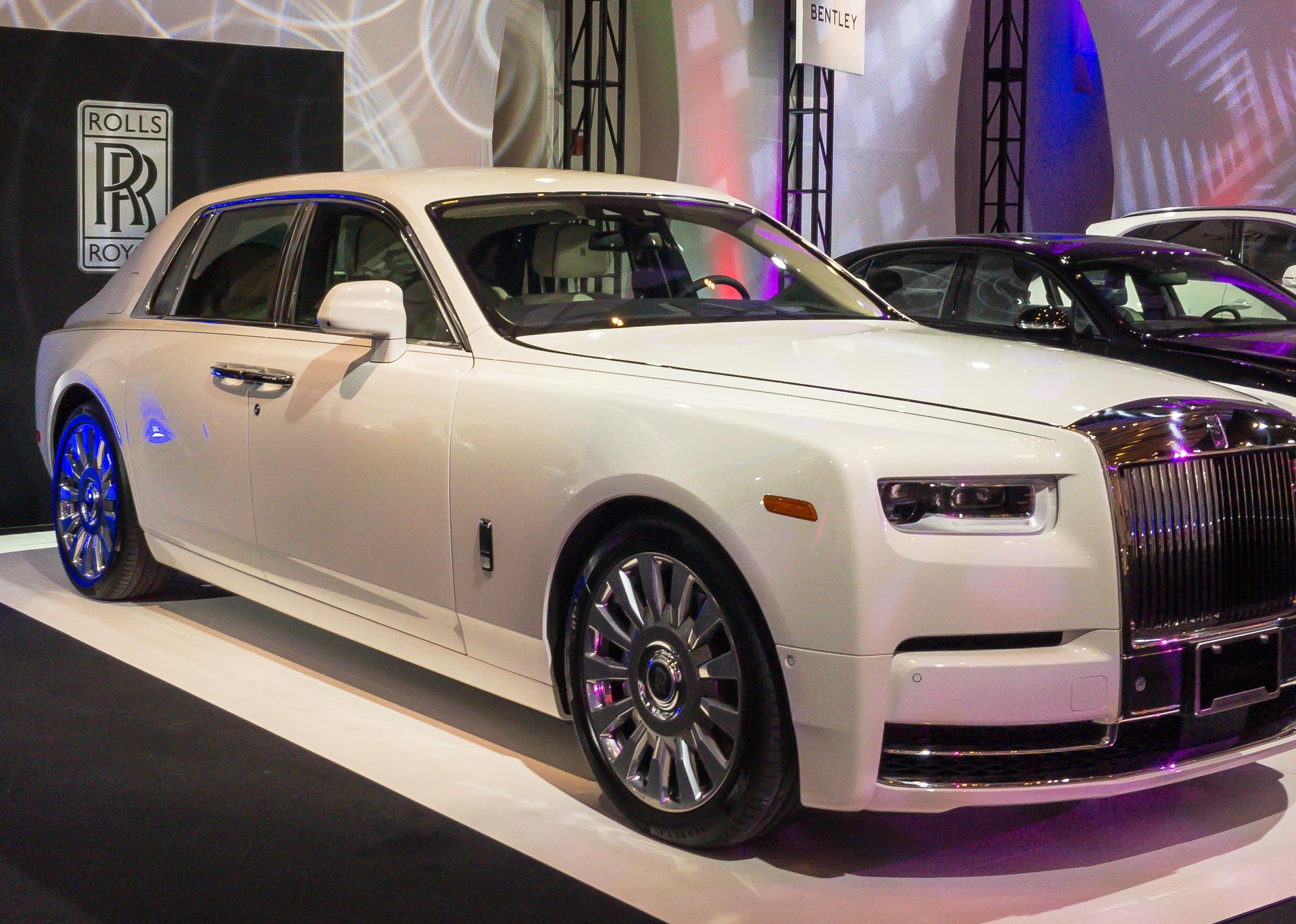 A white Rolls Royce Phantom on a showroom floor.