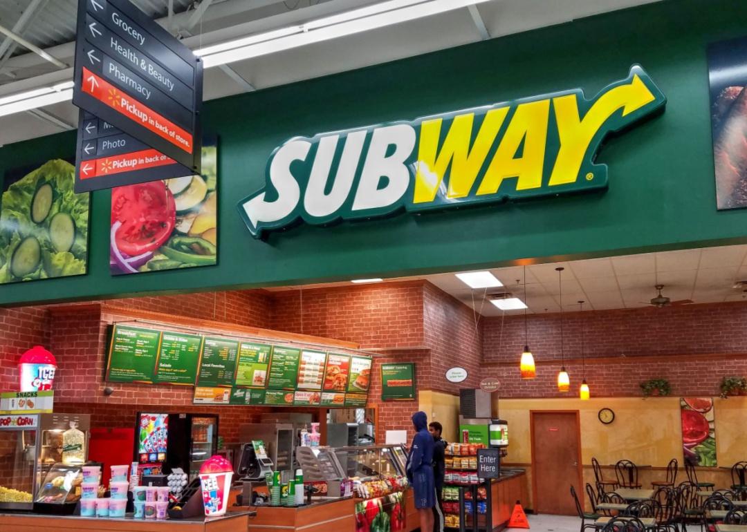 Two people ordering at a Subway sandwich shop.