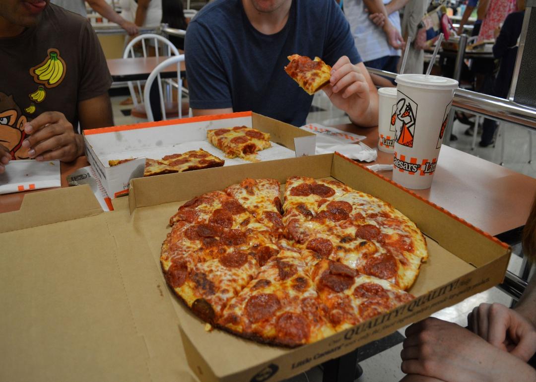 A table of people eating pizza at Little Caesars.