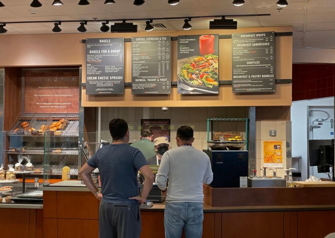 Two people ordering at a Panera Bread restaurant.