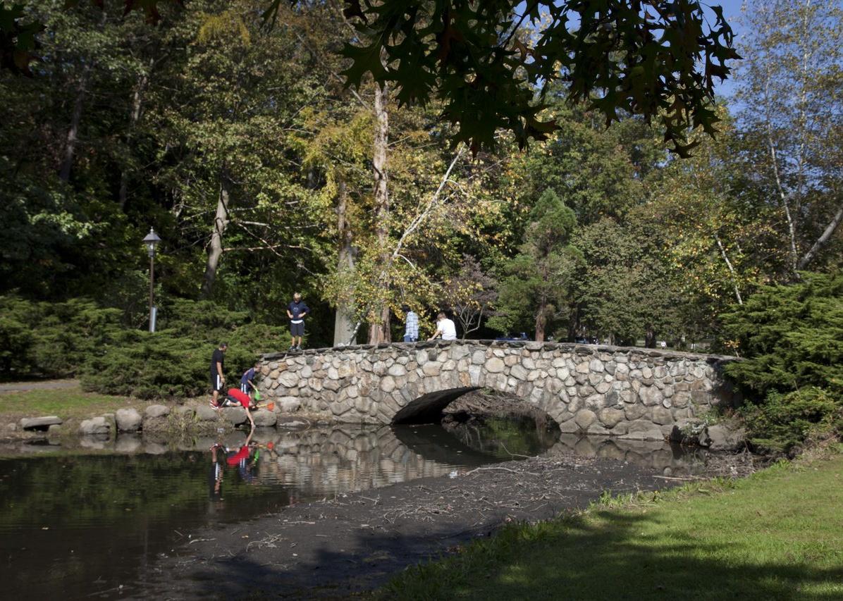 Kids playing on a stone bridge at a park.