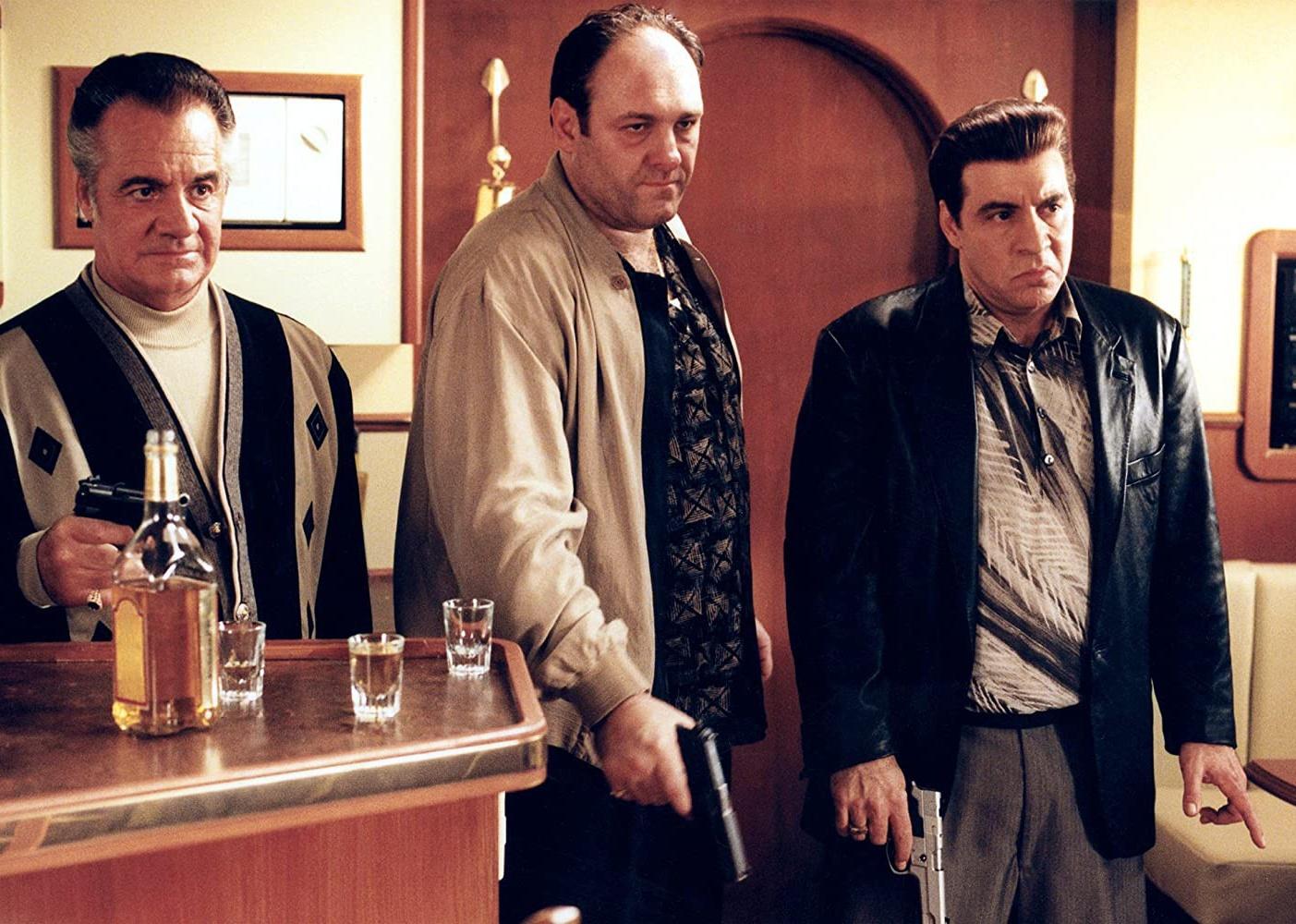 James Gandolfini, Tony Sirico and Steven Van Zandt stand behind a bar holding guns.