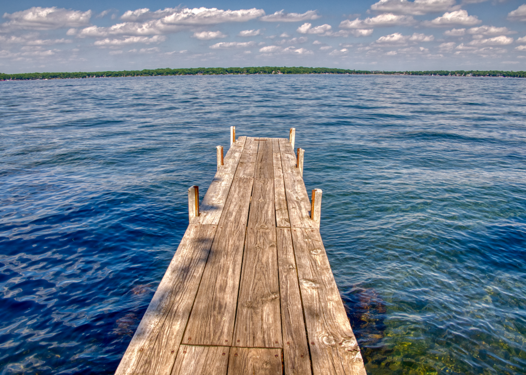 A wooden dock leading out to clear waters. 