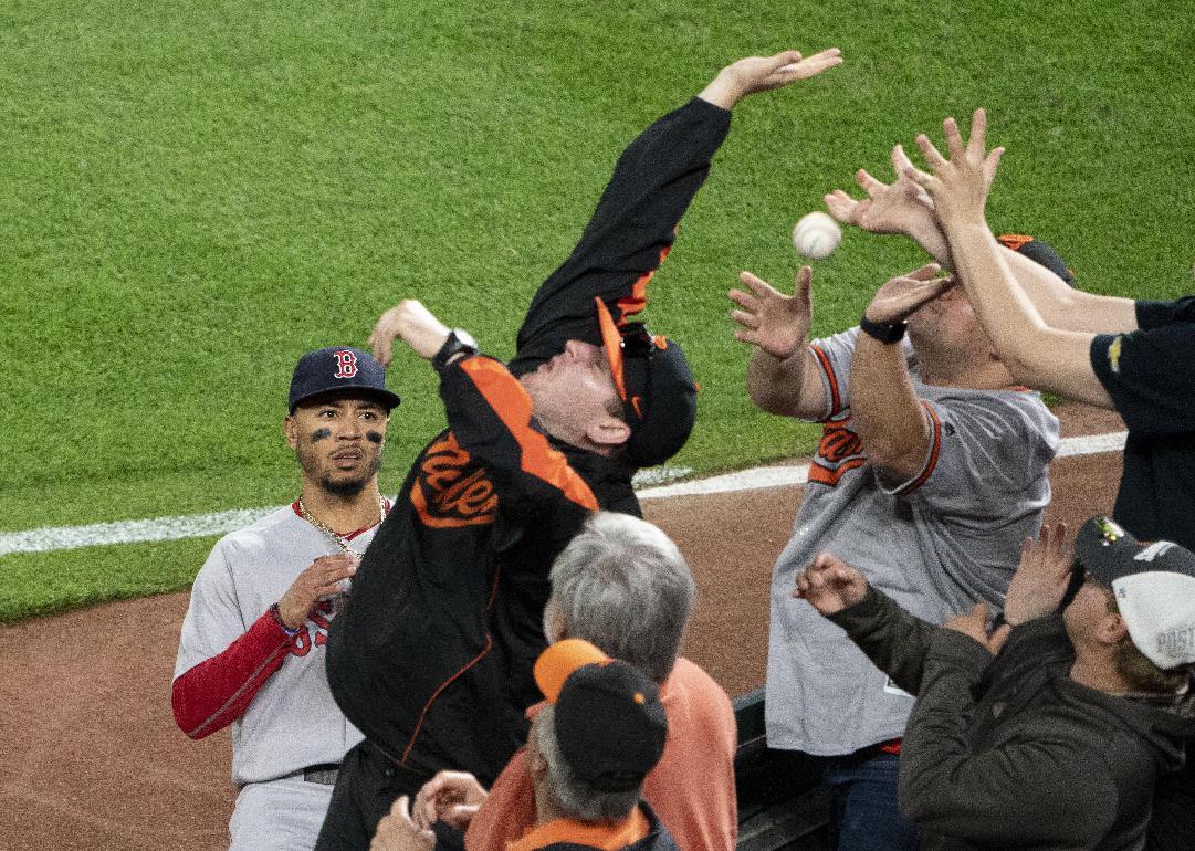 A professional baseball player and fans trying to catch a foul ball during a game. 