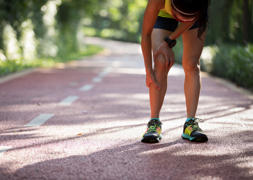 Female runner stopped on a track signaling pain in her leg.
