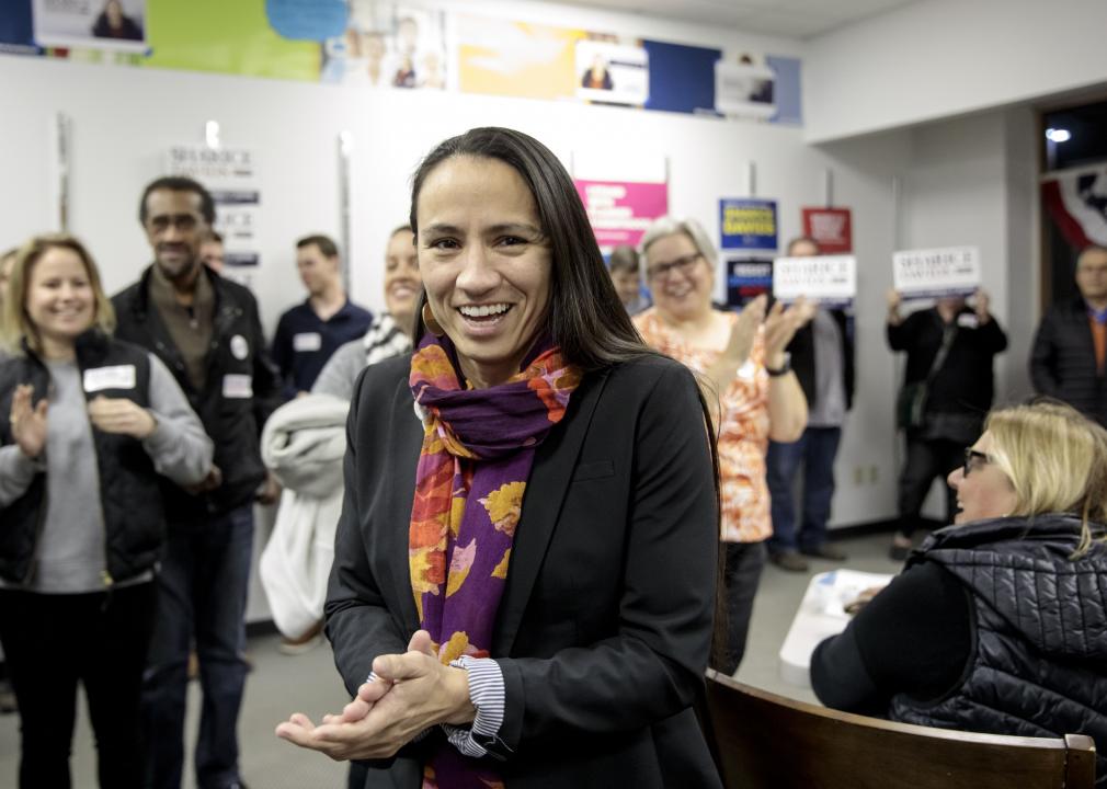Sharice Davids smiling and clapping her hands in a room with other people also smiling and clapping.