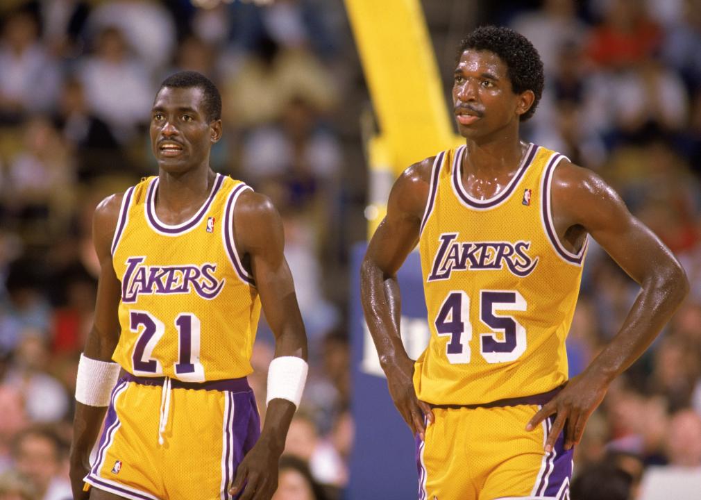 Michael Cooper of the Los Angeles Lakers stands next to A.C. Green during an NBA game.