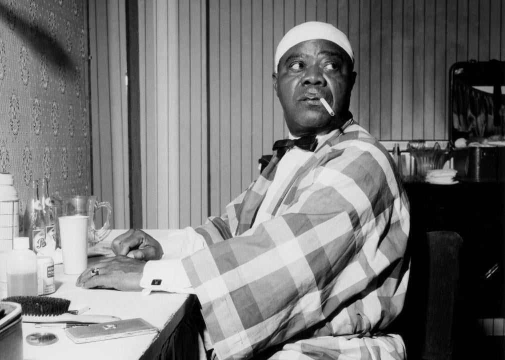Louis Armstrong relaxing backstage and smoking.