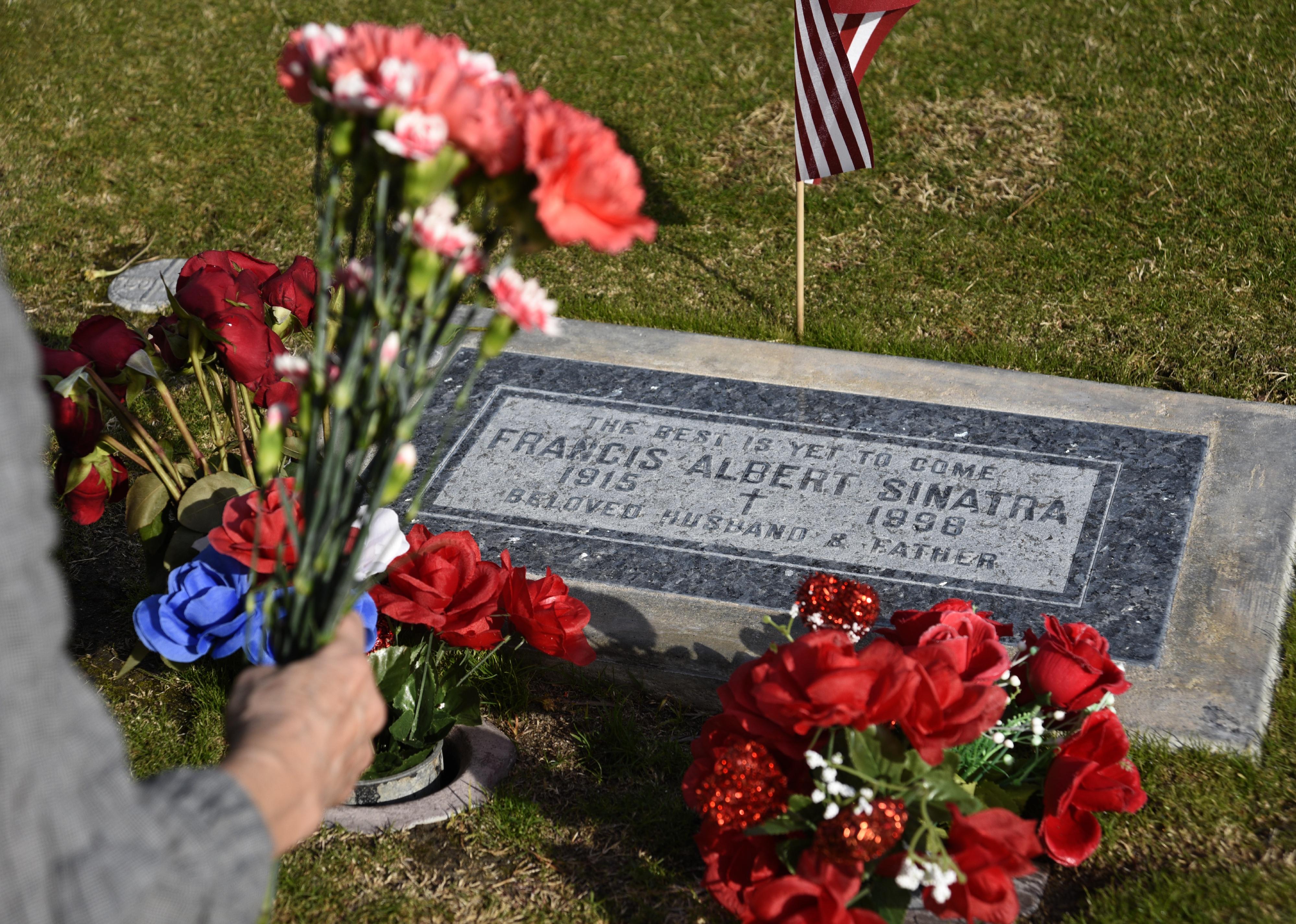 A woman places flowers on the grave of singer Frank Sinatra at Desert Memorial Park in Cathedral City.