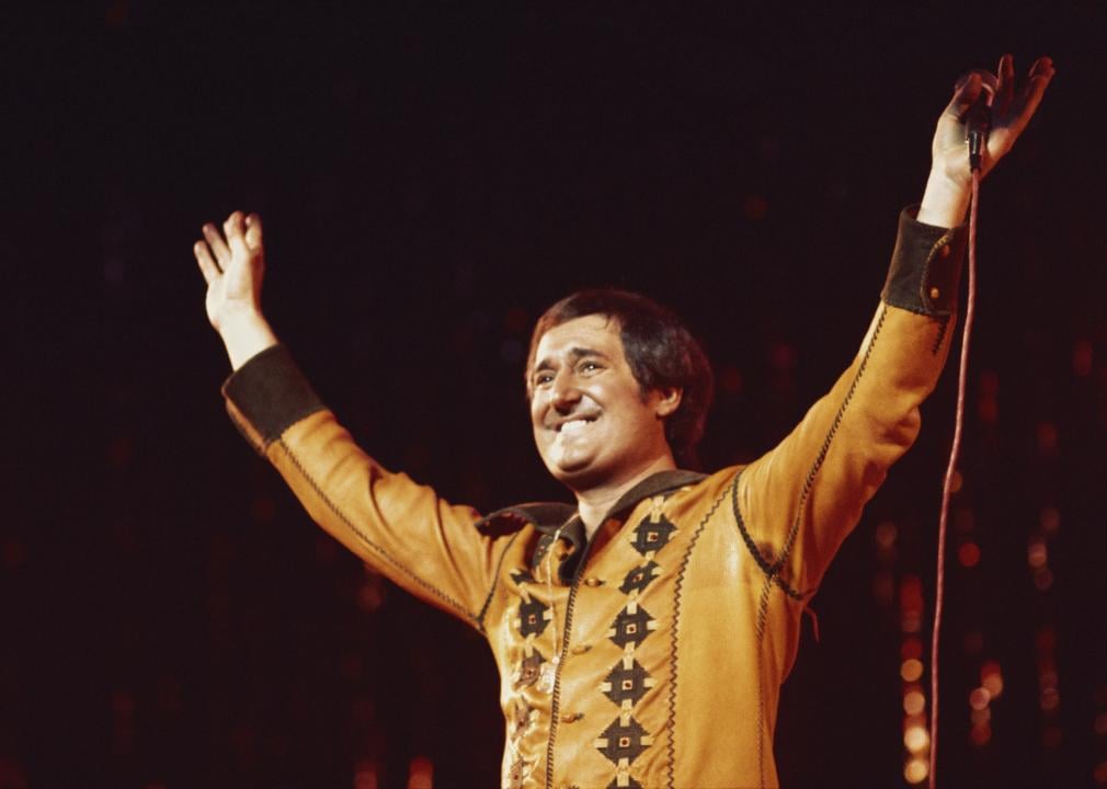 Neil Sedaka holding his hands in the air during a live concert performance.