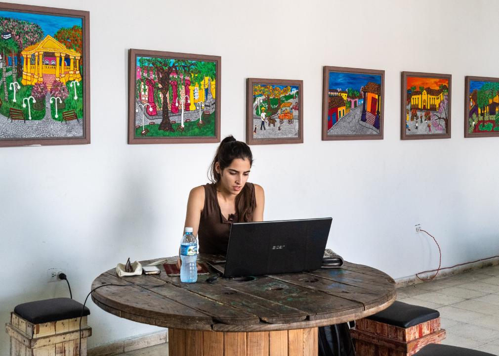 Young woman on a laptop in a Cuban gallery