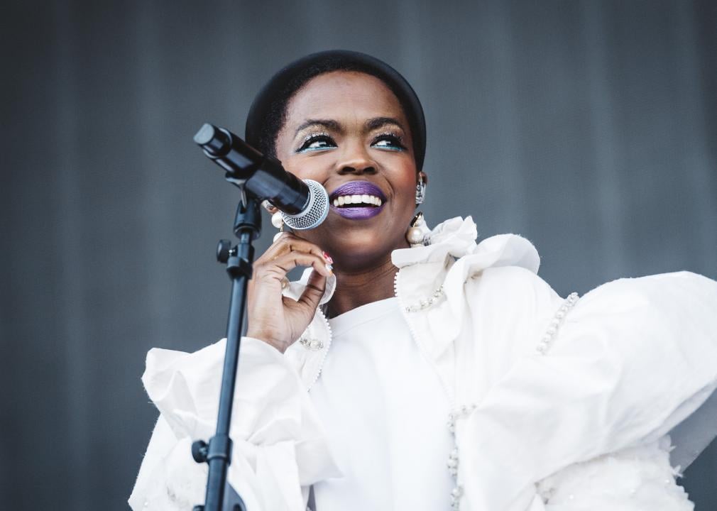 Lauryn Hill performing onstage in white dress.