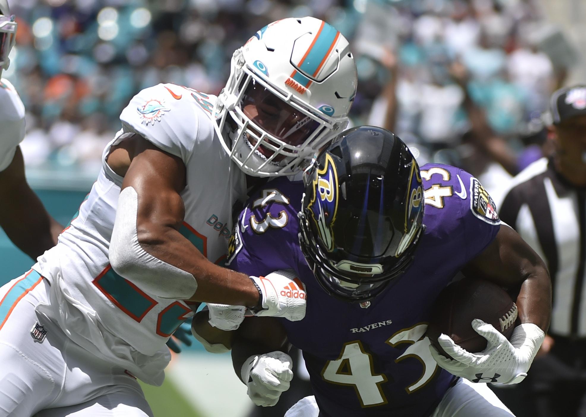 Minkah Fitzpatrick of the Miami Dolphins knocks Justice Hill of the Baltimore Ravens out of bounds.