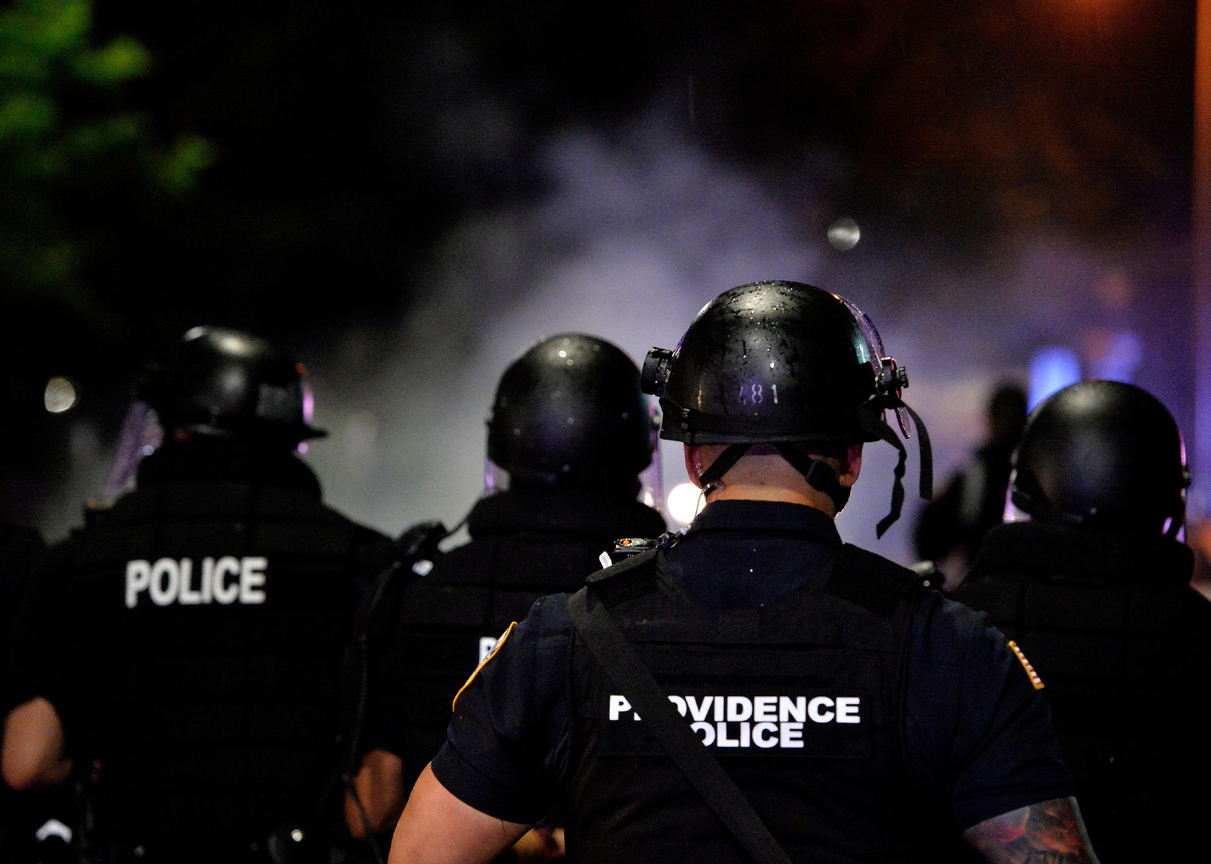 Police officers make their way through a smoke filled street in Providence, Rhode Island.