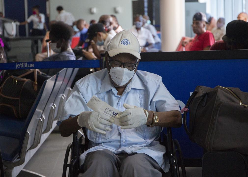 A man wearing mask and gloves waits in a wheelchair to board a flight run by JetBlue