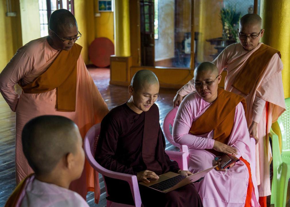 Group of Buddhist nuns in Myanmar looking at a laptop
