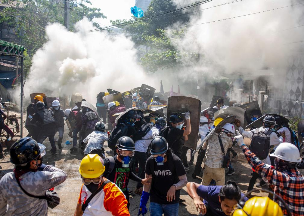 Protesters react after riot police fired tear gas canisters