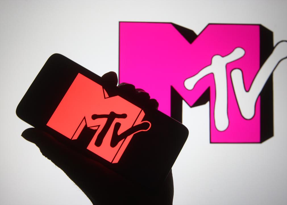 A silhouette hand is seen holding a smartphone with MTV channel logo.