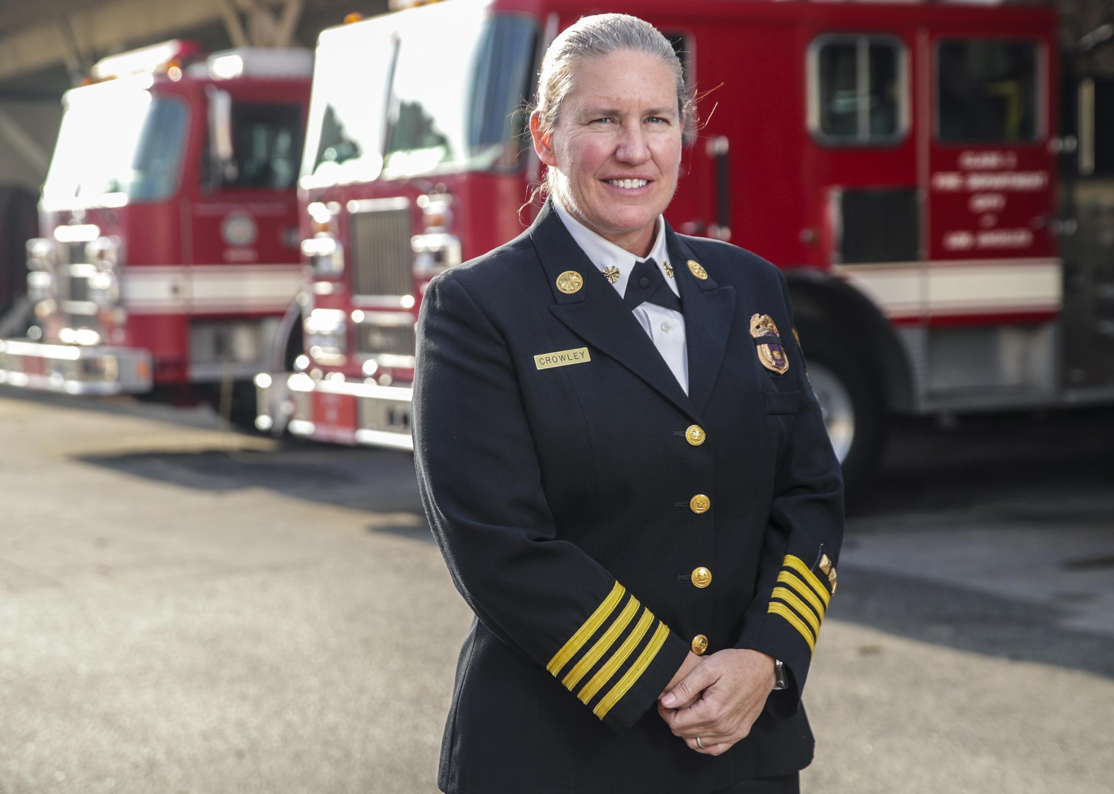 Deputy Fire Chief Kristin Crowley poses in front of fire trucks.