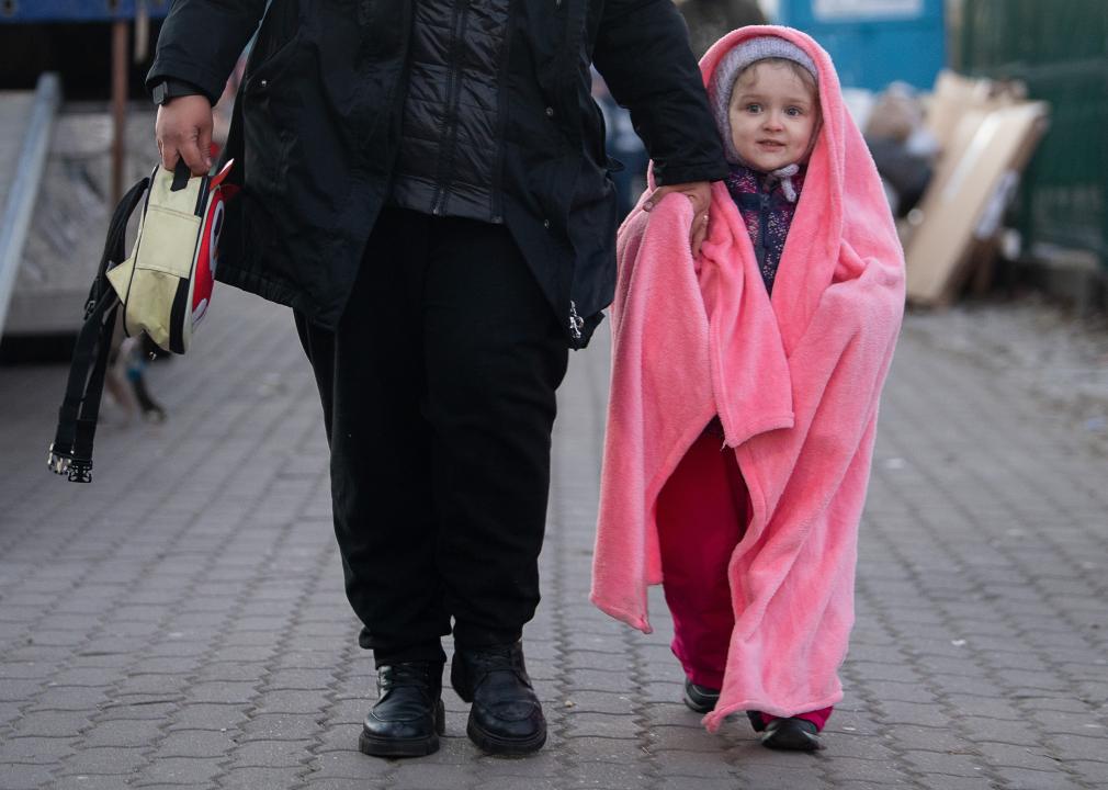 Small bundled up child walking in hand with her mother
