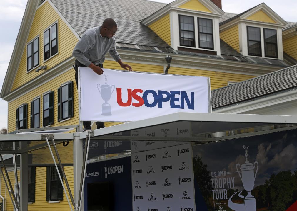 Jermaine Blake sets up a US OPEN sign in front of The Country Club