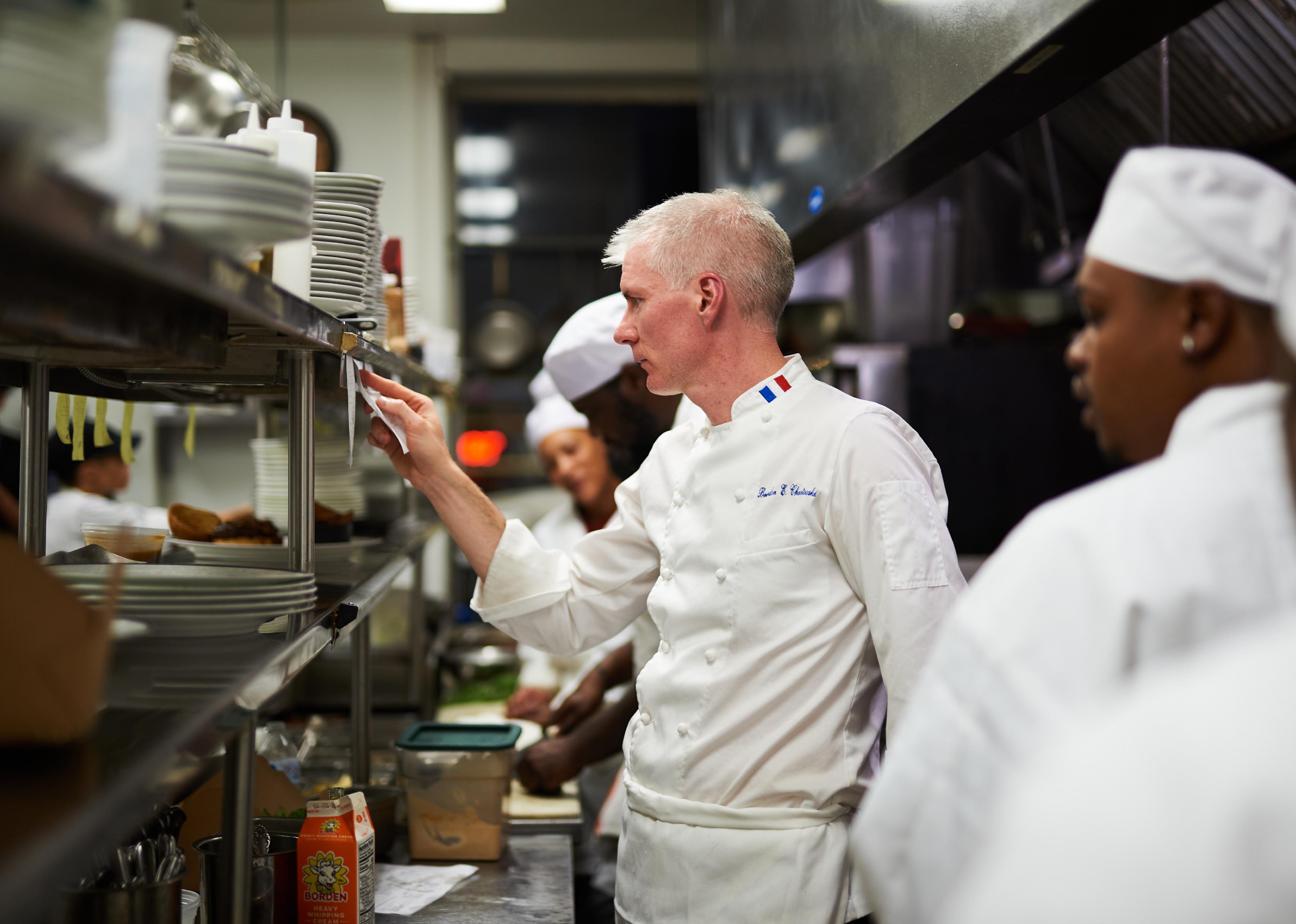A chef works with his employees at a restaurant