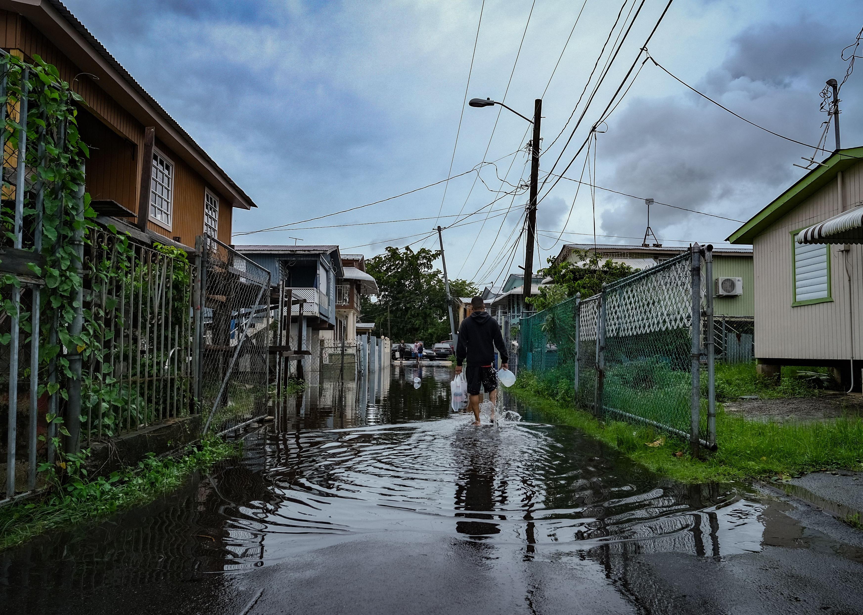 A man walks down a flooded street in the Juana Matos neighborhood of Catano, Puerto Rico.