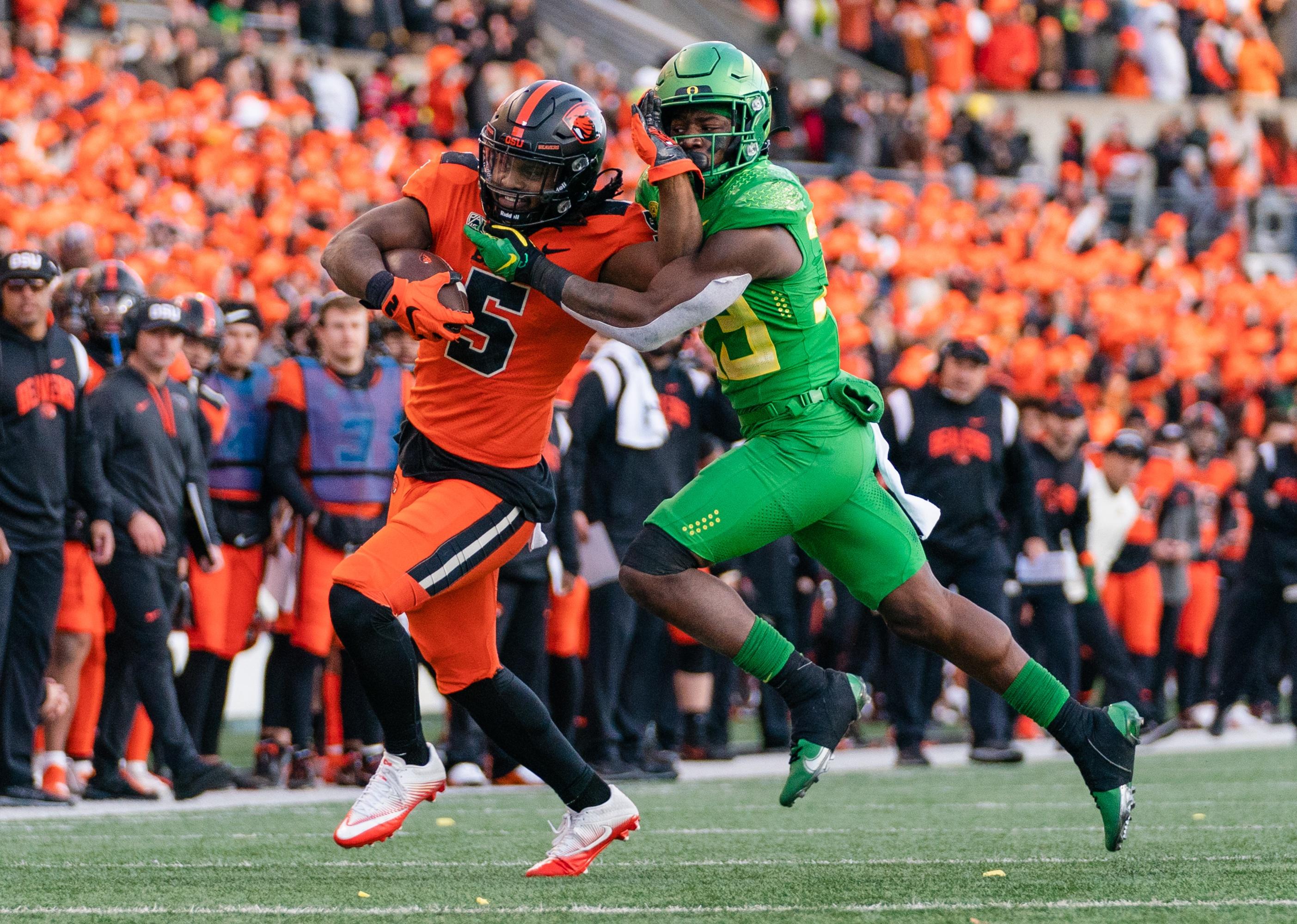 Deshaun Fenwick of the Oregon State Beavers fends off Jeffrey Bassa of the Oregon Ducks.