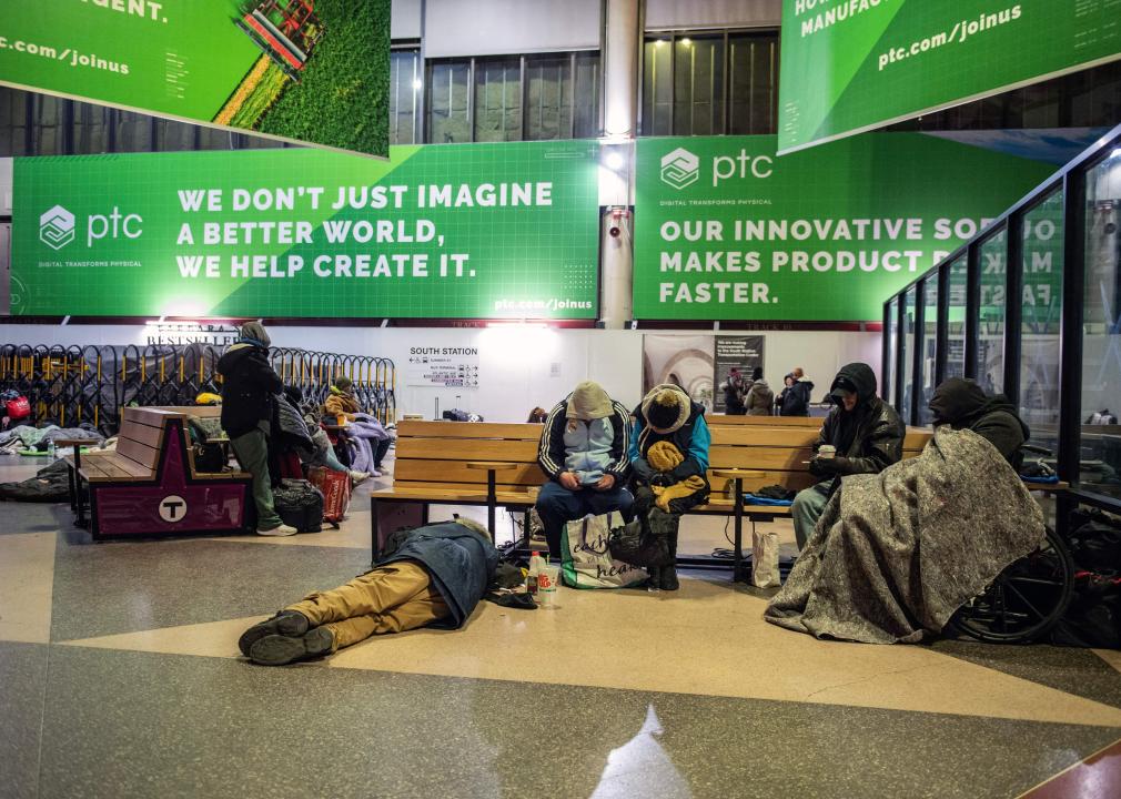 People sitting and sleeping on the floor and on benches at South Station in Boston.