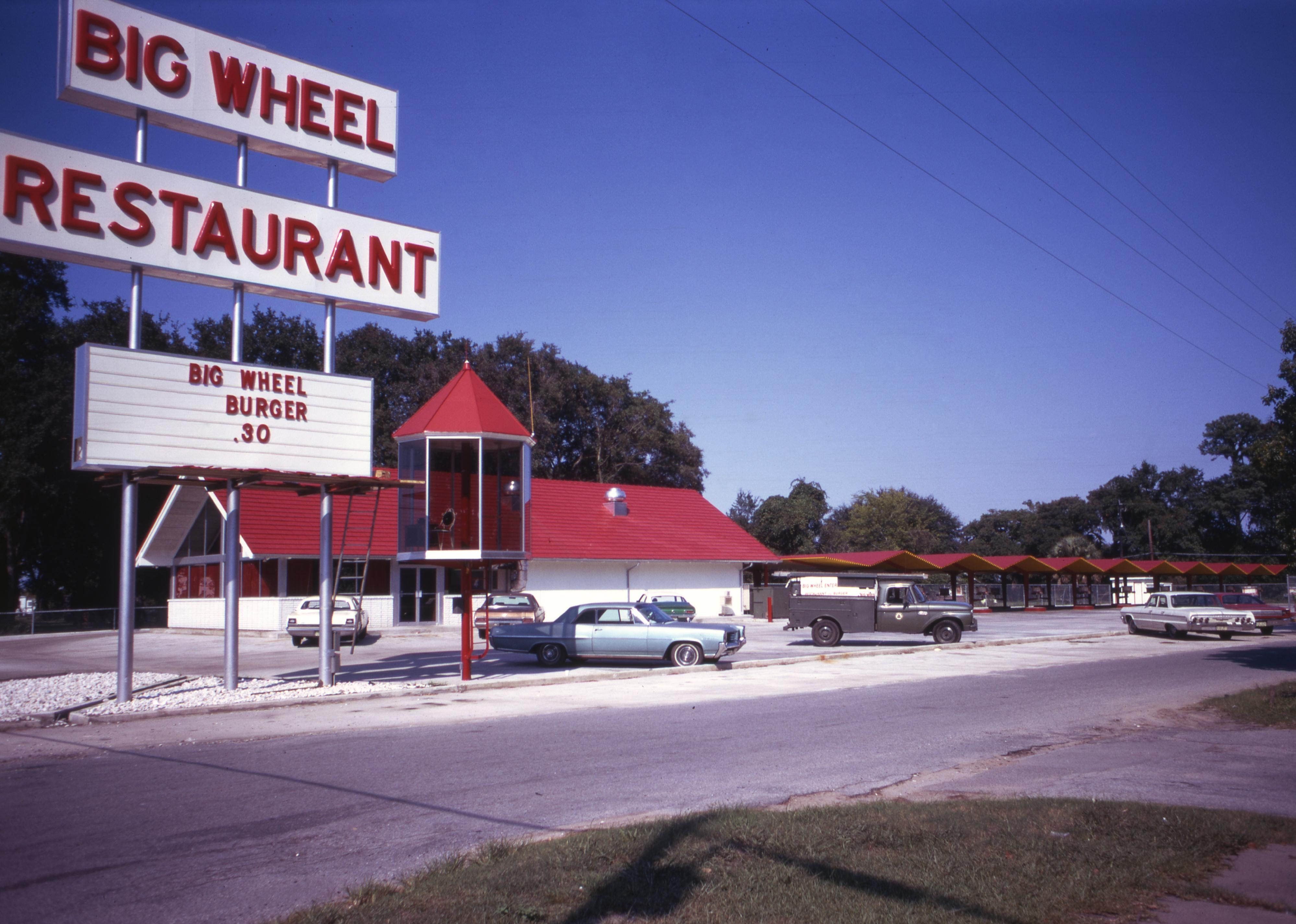 Cars parked outside of a Big Wheel Restaurant with a sign for Big Wheel Burgers for 30 cents, 1971.