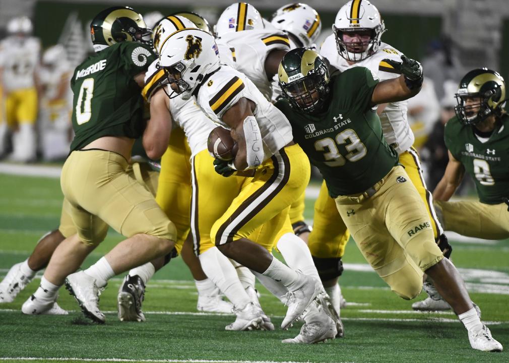 Wyoming Cowboys running back Xazavian Valladay tries and can't escape from the defense of Colorado State Rams defensive lineman Manny Jones