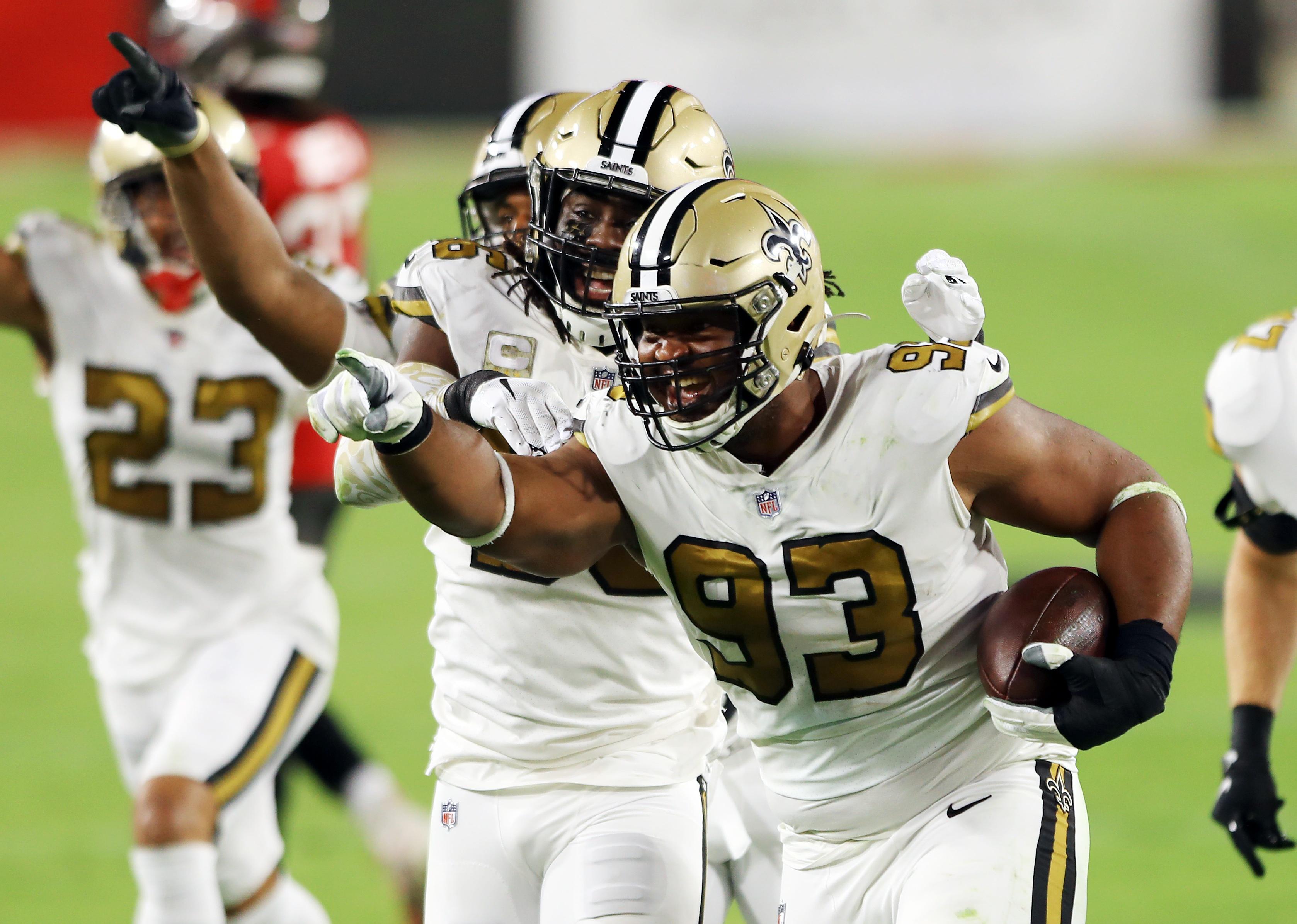 David Onyemata of the New Orleans Saints celebrates with teammates after intercepting a pass.