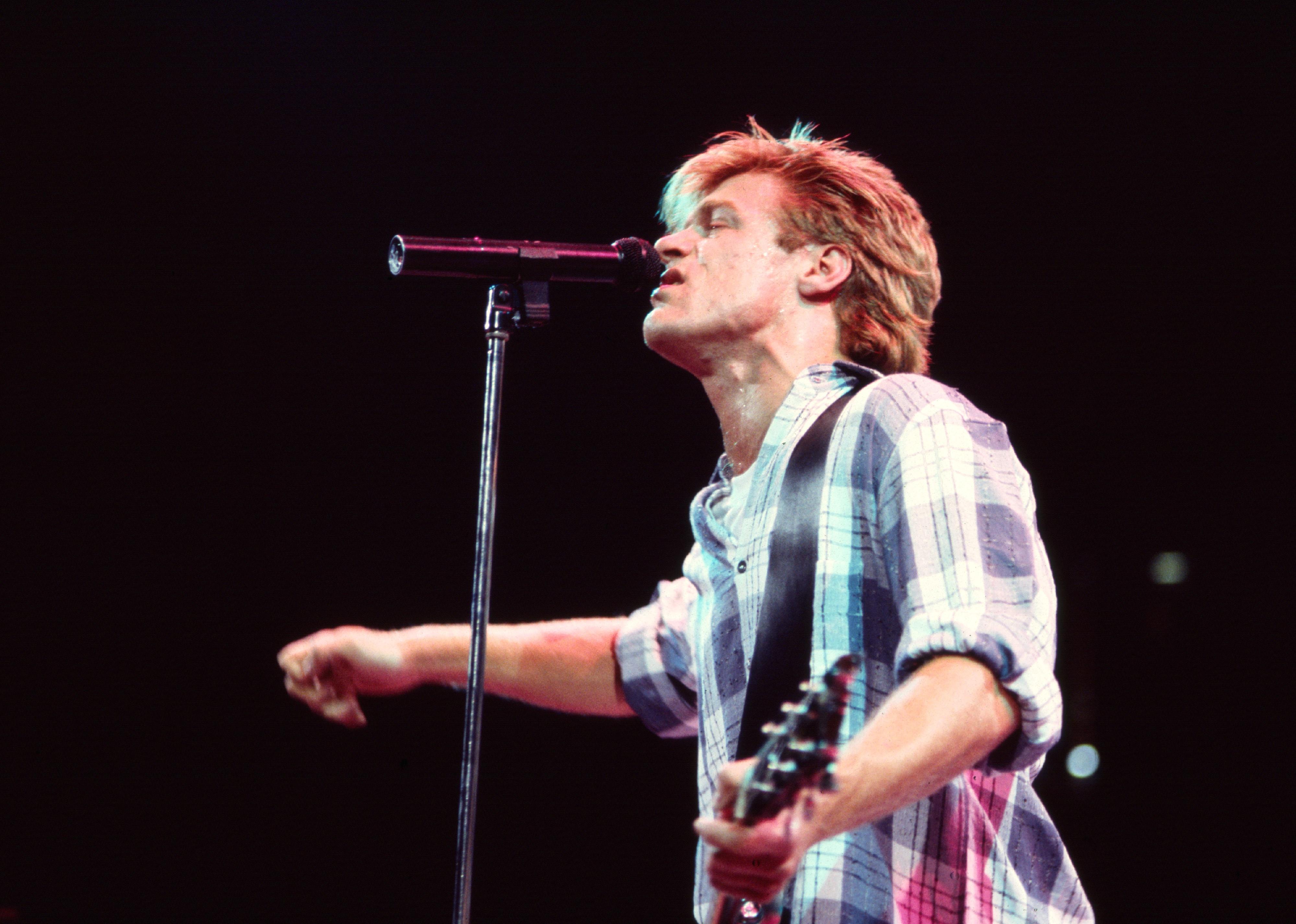 Bryan Adams plays guitar as he performs onstage during the Reckless tour.